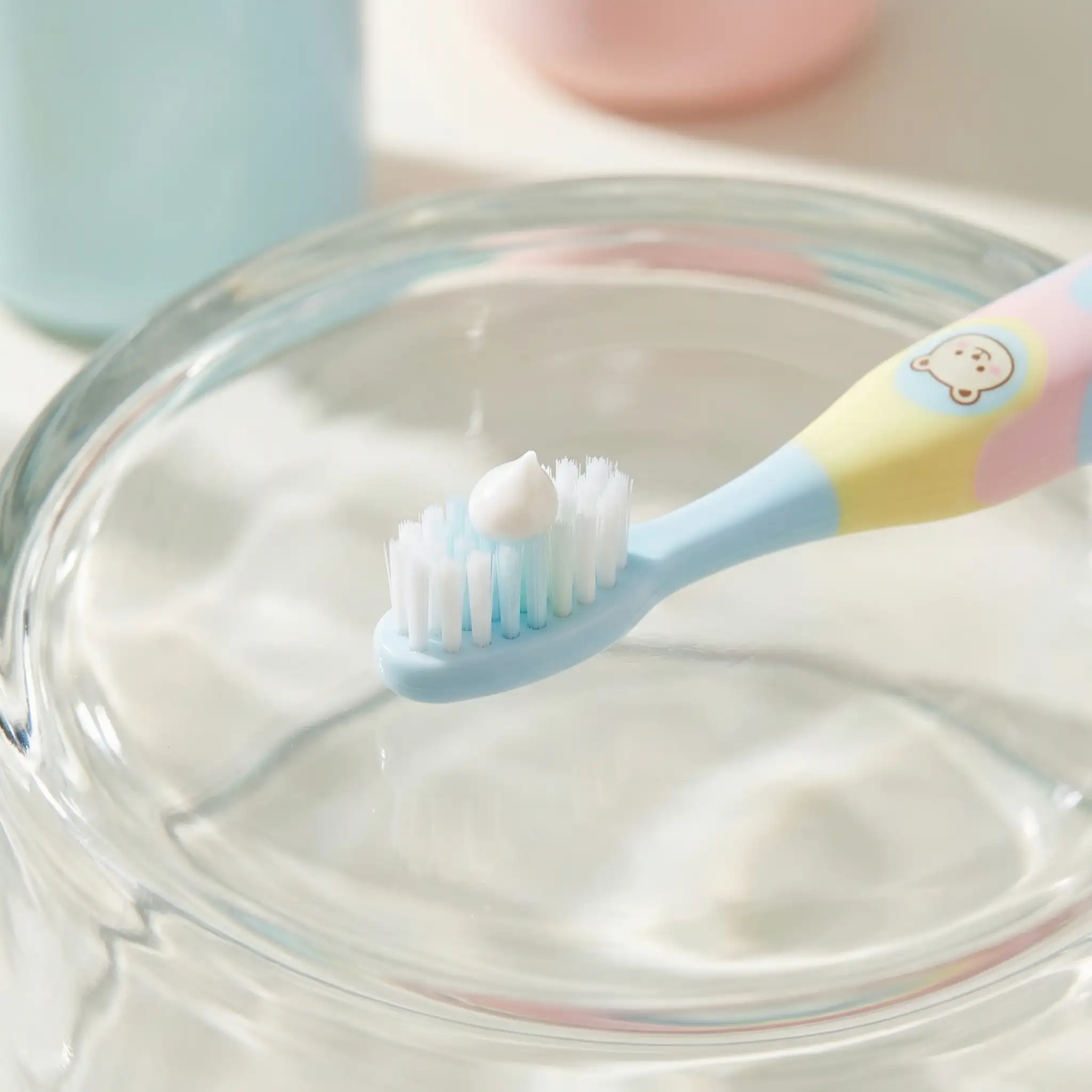 Bright pastel children's toothbrush with a drop of toothpaste
