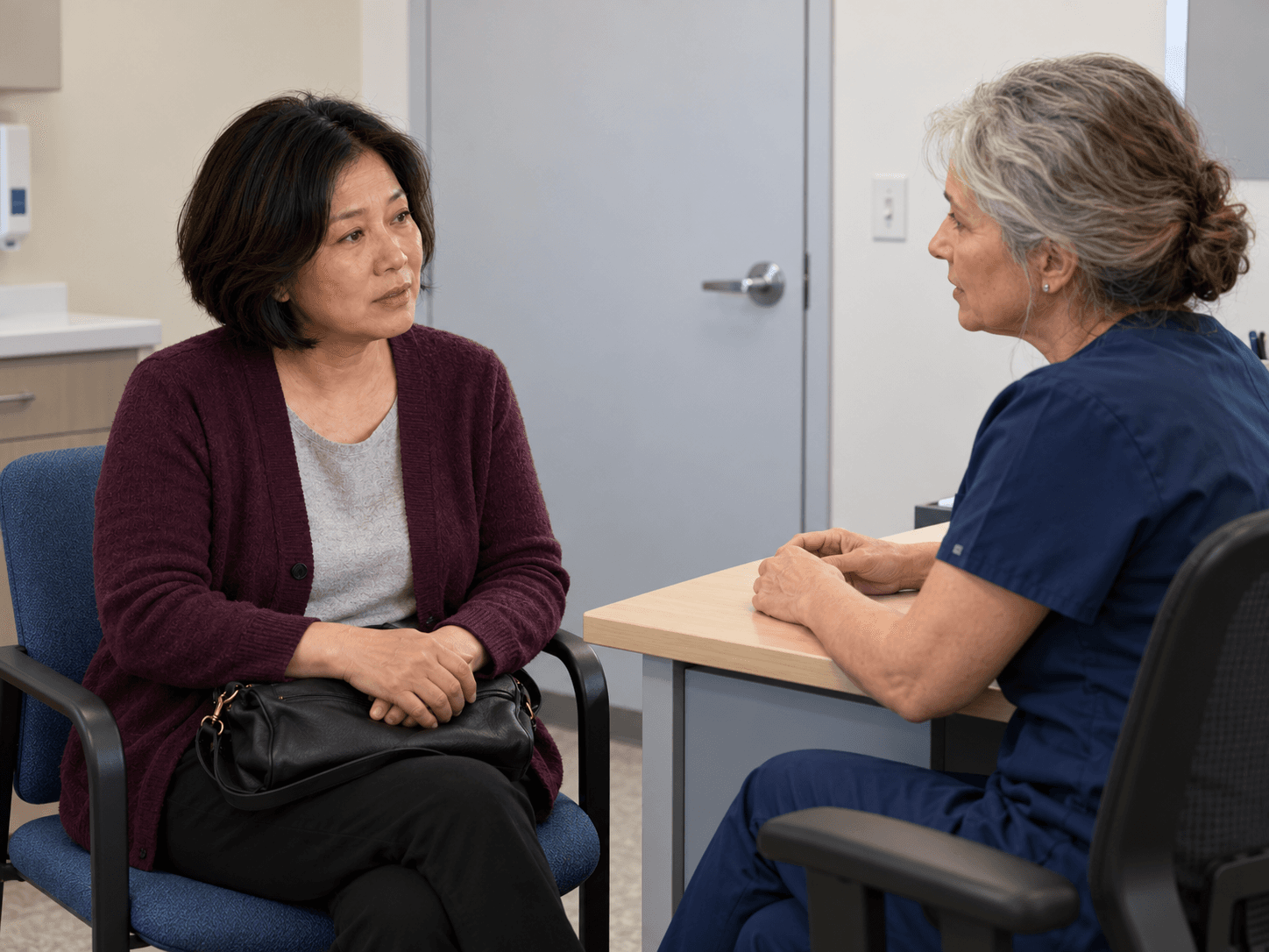 The woman listens to a clinician during a biopsy follow-up conversation.