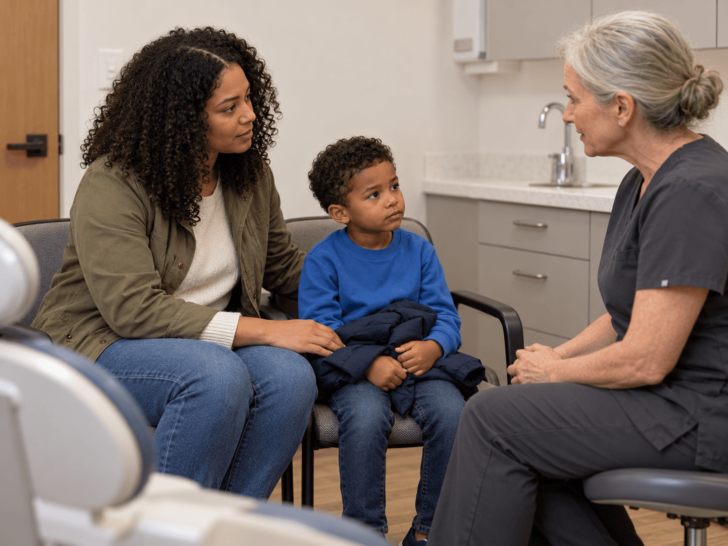 A mother asks a dentist about a treatment plan with her child seated beside her.
