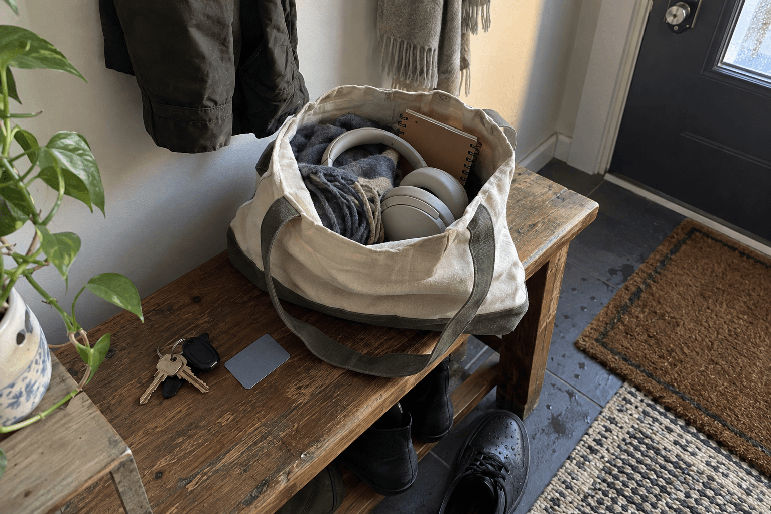 Headphones, a scarf and a notebook packed in a canvas tote by the front door.