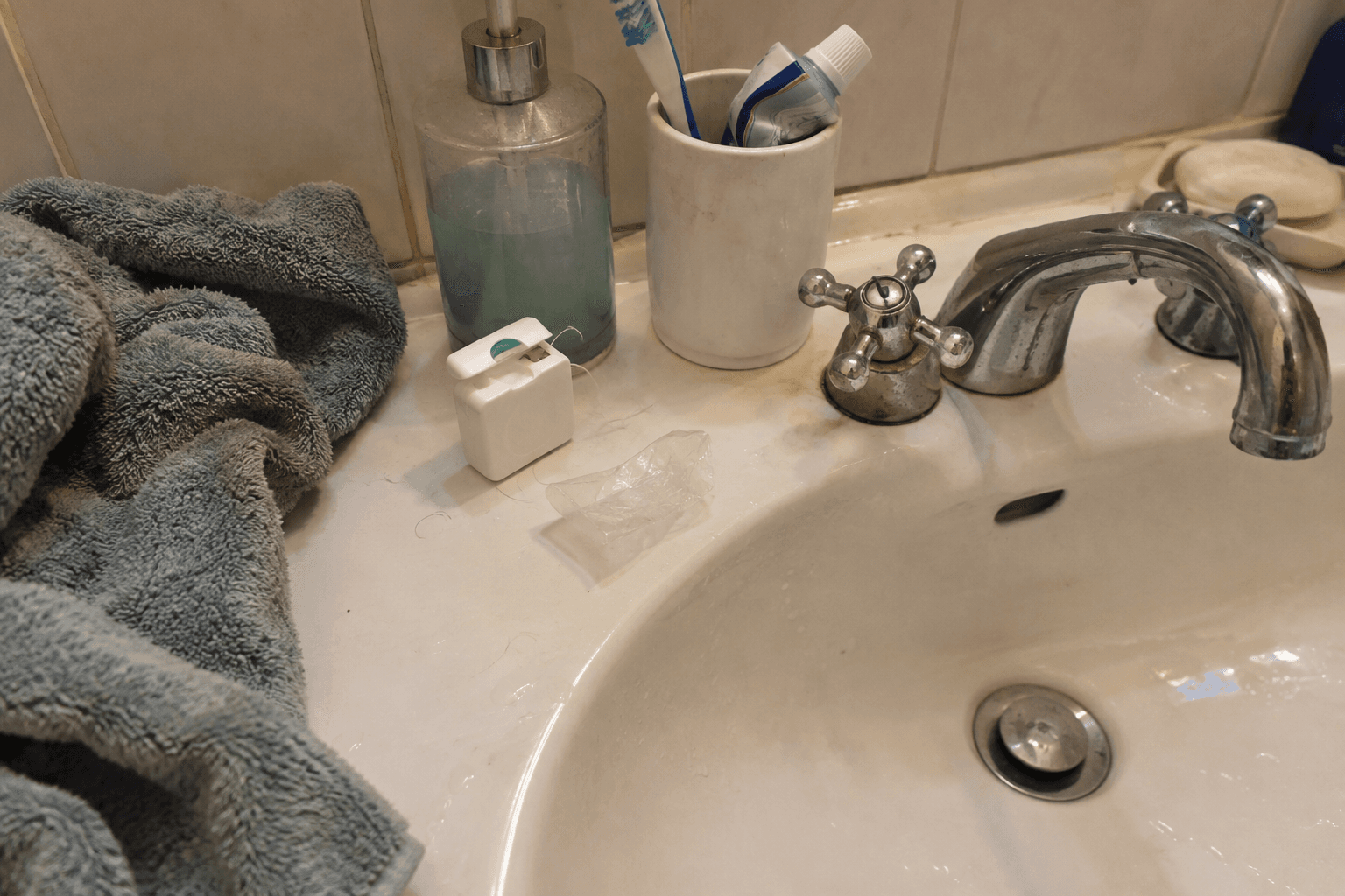 Floss and its opened wrapper beside a bathroom sink.